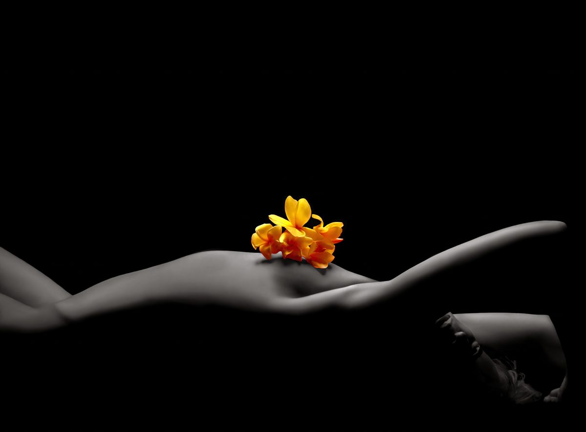 A naked woman laying on her back with a flower on her chest.