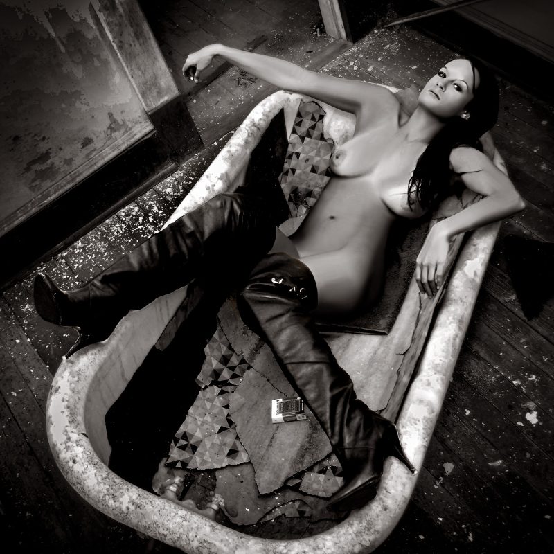 A naked woman laying in a bathtub.
