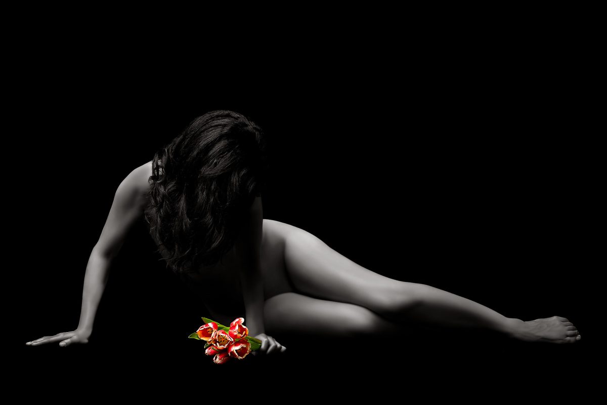 A naked woman with a bouquet of red and white flowers in her hand.