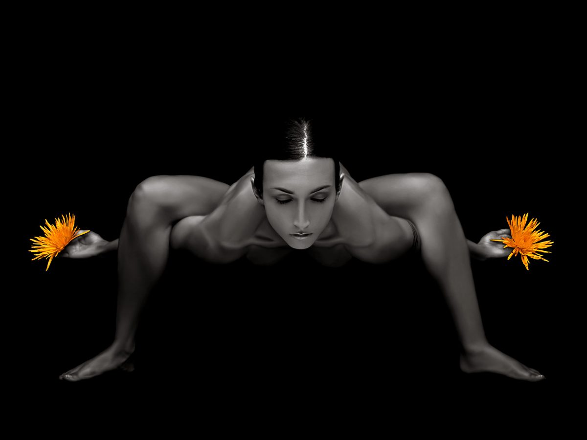 A naked woman in a yoga pose with flowers in her hands.