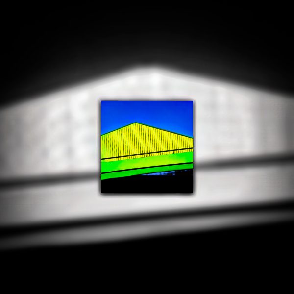 A yellow and green building against a blue sky.