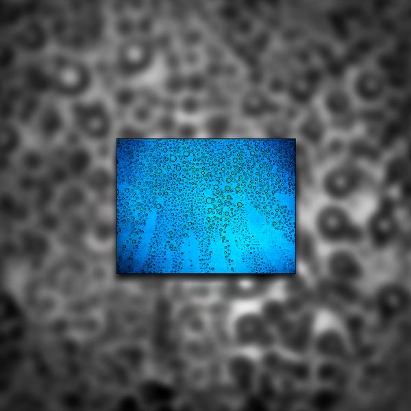 A blue and black photograph of water droplets on glass with a darker background.