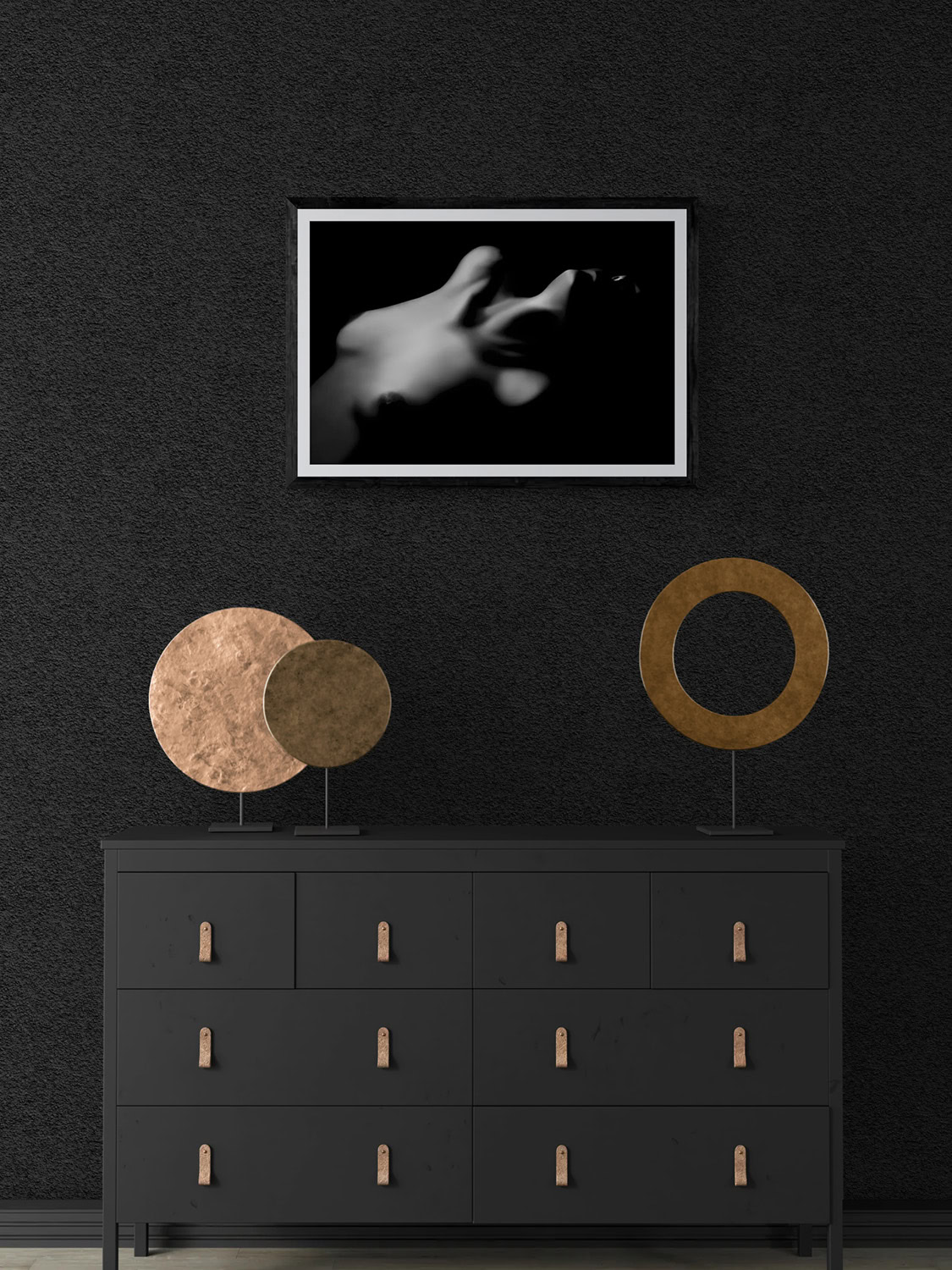 Black and white abstract hand sculpture with circular art pieces on a dark wall.