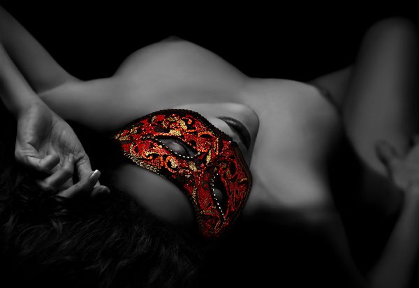 A woman laying on her back with a red mask on her face.