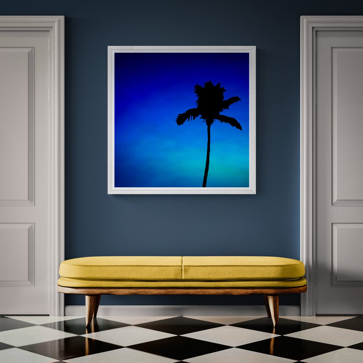 Silhouette of a palm tree against a vibrant blue sky.