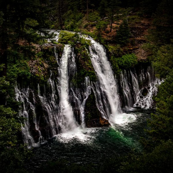 Waterfall scene in lush forest landscape, part of The Doug Heslep Fine Art Collection.