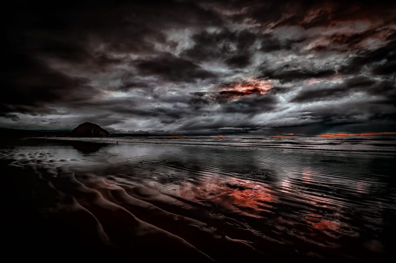 Mysterious stormy ocean scene with dark clouds, rugged shoreline, and dramatic reflections.