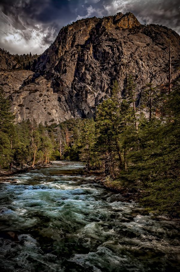 Vibrant mountain landscape featuring a rushing river and towering rocky cliffs, capturing the essence of the Doug Heslep Fine Art Collection.