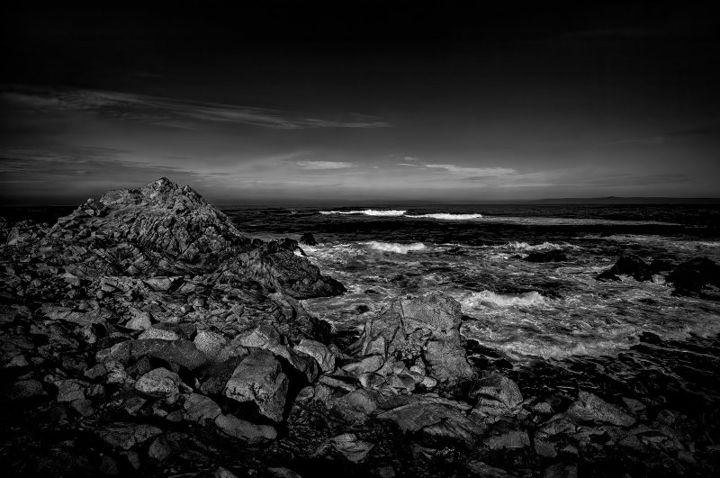 Clouds over rocky shoreline in black and white, dramatic ocean scene, The Doug Heslep Fine Art Collection, stunning monochrome landscape artwork, seascape photography.