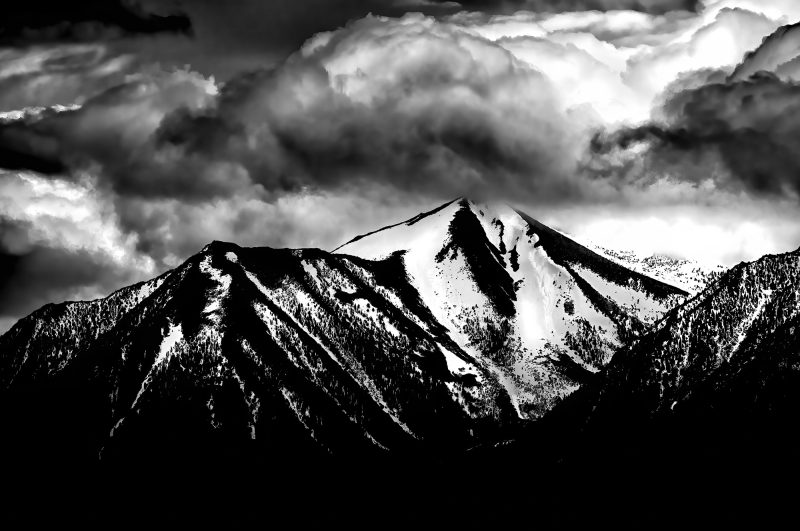 Snow-capped mountain peak with dramatic clouds in black and white, part of The Doug Heslep Fine Art Collection.