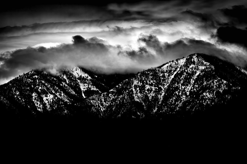 Snow-capped mountain range with dramatic clouds in black and white landscape photography