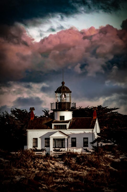 Lighthouse at sunset in the Doug Heslep Fine Art Collection, showcasing dramatic clouds and coastal scenery.