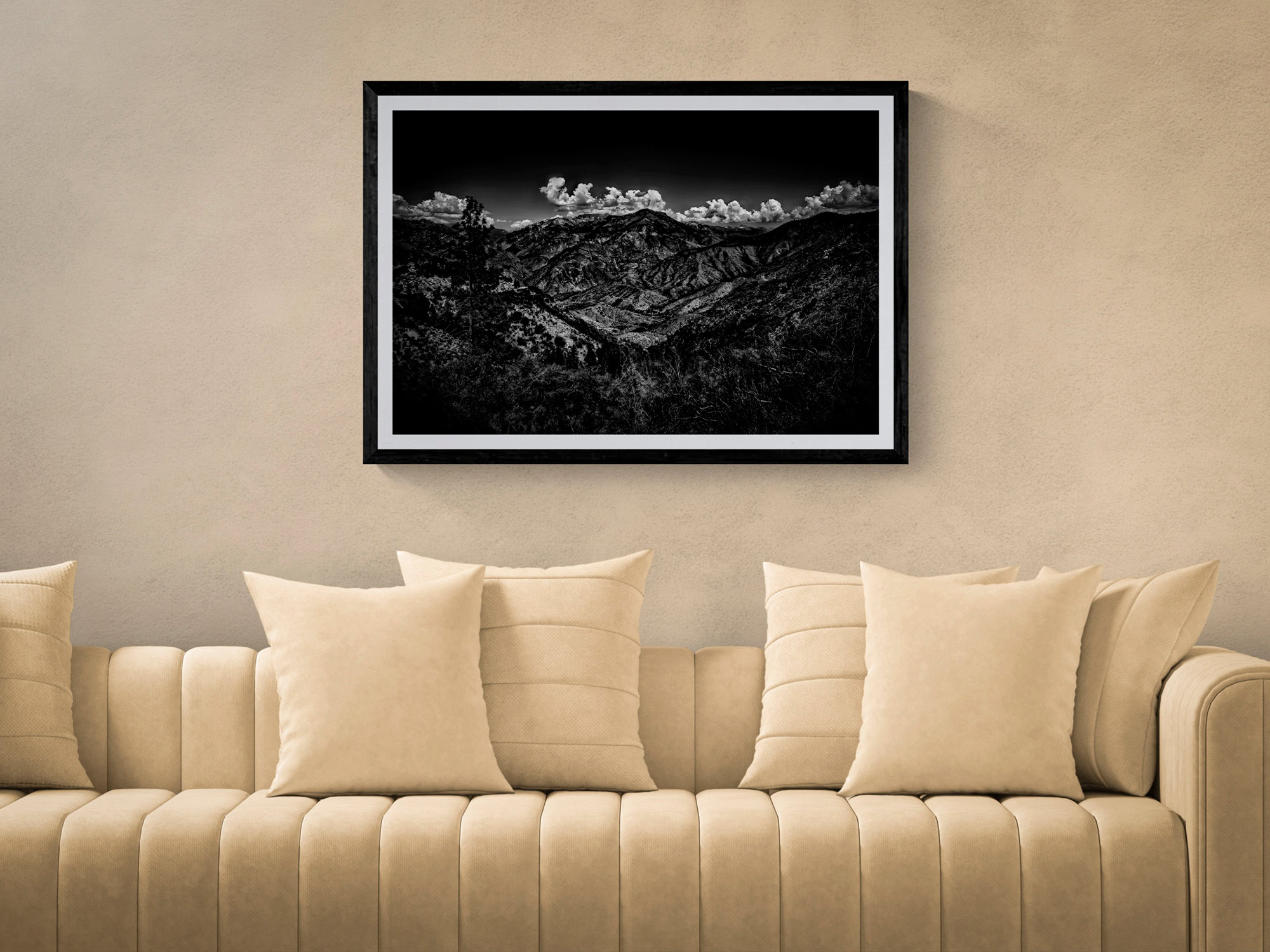 Mountain landscape photograph in black and white, framed and hung on a neutral wall above a beige so.