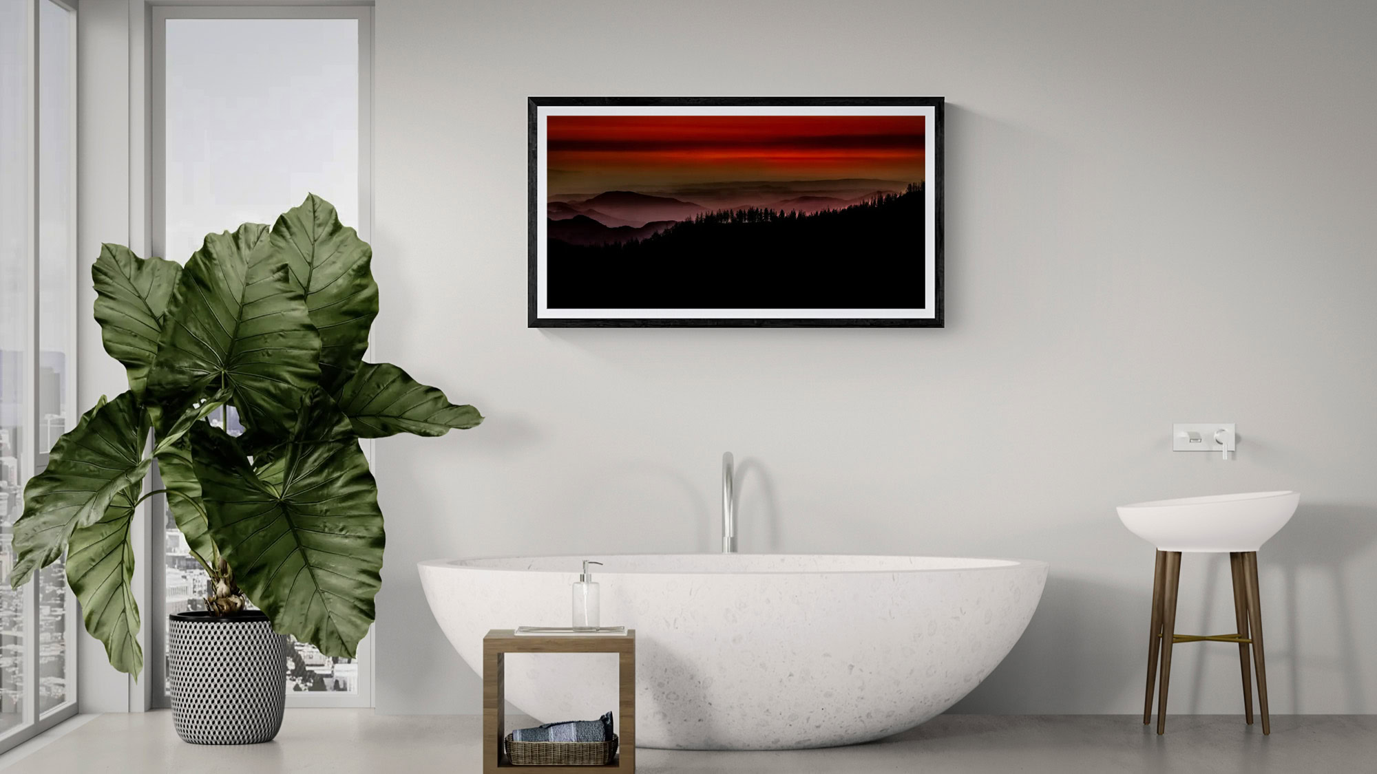 Landscape art featuring a sunset over mountains, displayed above a modern freestanding bathtub.