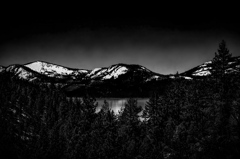 Snow-capped mountains near a lake in the Doug Heslep Fine Art Collection, showcasing stunning nature photography.