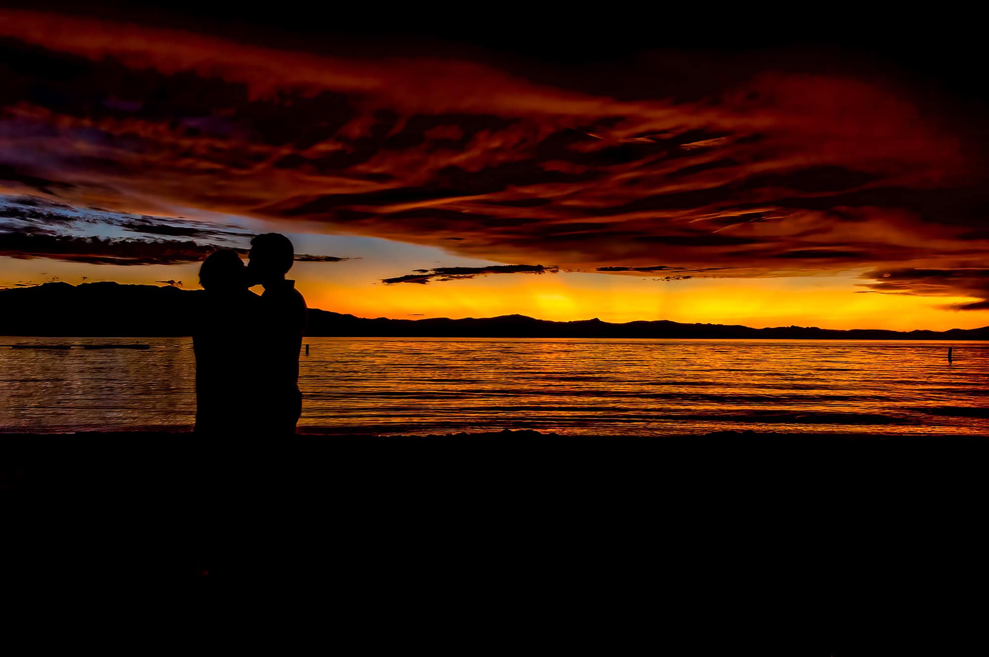 A couple kissing in silhouette framed by a sunset on Lake Tahoe