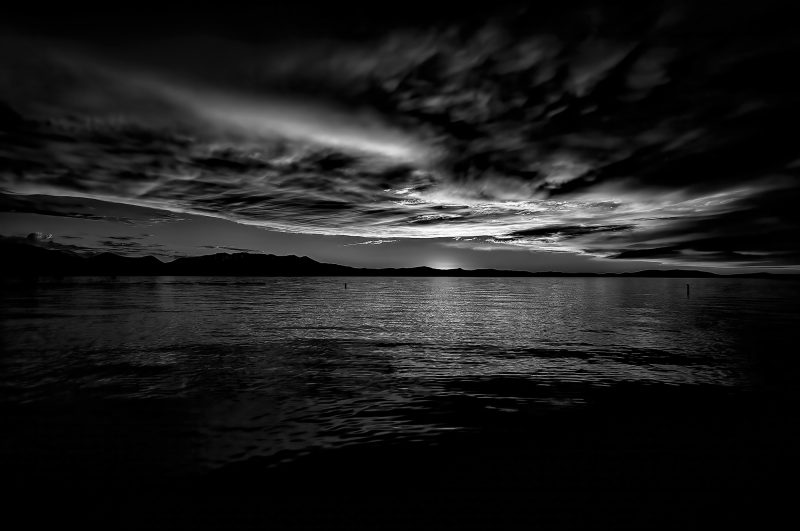 Stormy night over a calm lake with dramatic clouds in black and white.