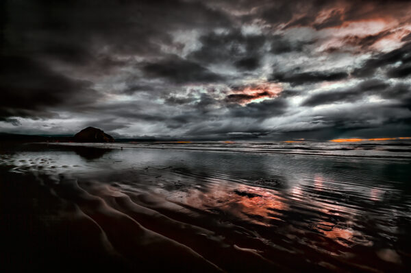 Morro Rock silhouetted by a soothing sunset as seen from Morro Strand State Beach