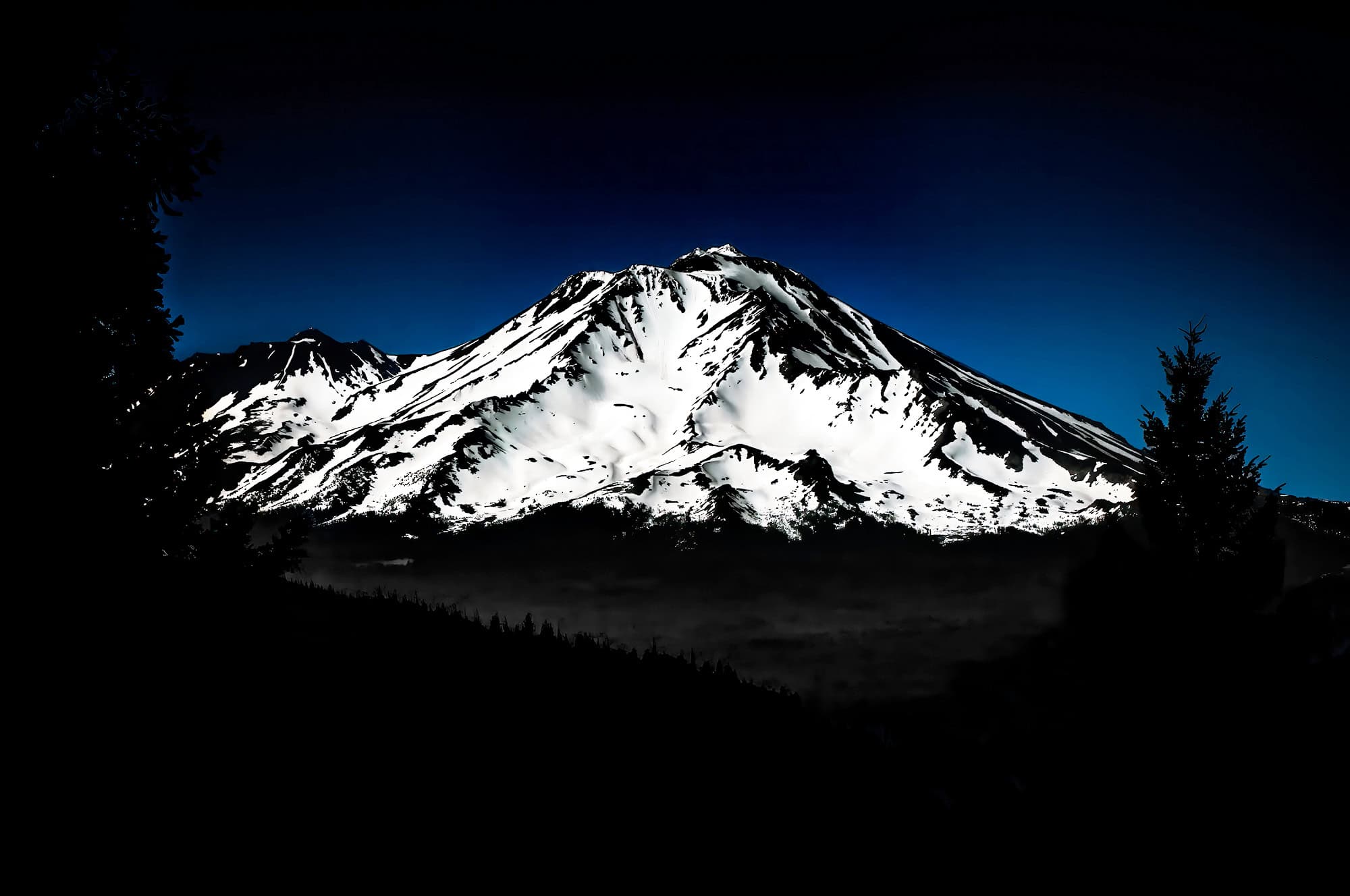 A snow covered Mount Shasta with a cool blue sky background