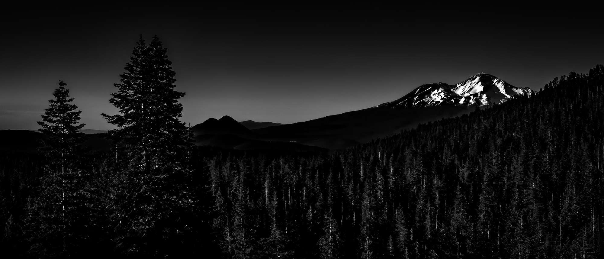 A black and white photo of an evening view of Mount Shasta and Black Butte as seen from Castle Lake