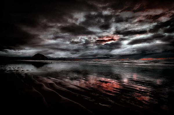 Morro Rock silhouetted by a soothing sunset as seen from Morro Strand State Beach