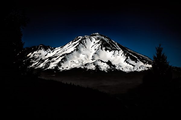 A snow covered Mount Shasta with a cool blue sky