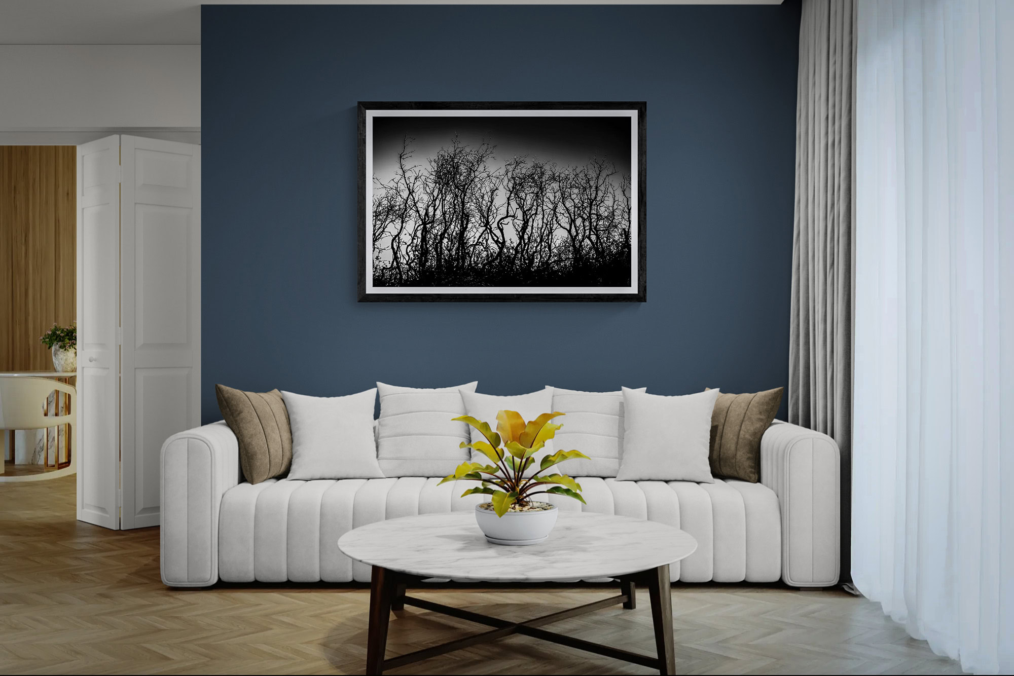 Black and white landscape photograph of leafless trees in a modern living room.
