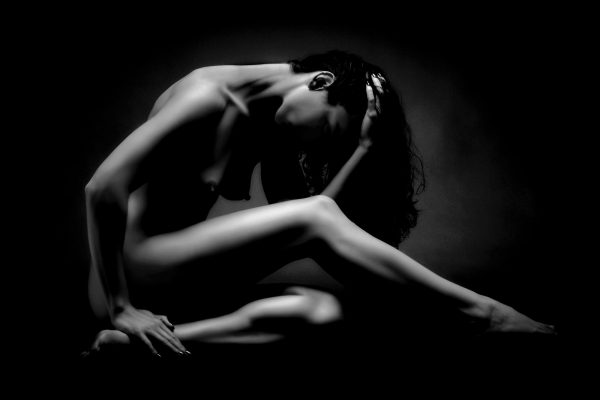 Hidden Contemplation by Doug Heslep, black-and-white fine-art figurative photograph exploring sculptural form, graceful movement, and introspective stillness through dramatic light and deep shadow.