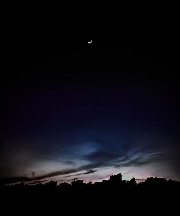 Moonset over Pacific Grove with twilight sky and silhouetted landscape.